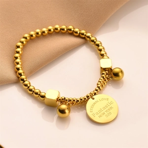 Golden titanium steel beaded bracelet featuring engraved round tag and geometric charms