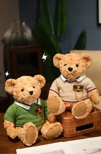 Detail of plush teddy bears in green and beige knit sweaters with embroidery on a cozy background