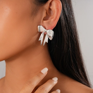 Close-up of elegant silver bow earrings with polished metallic finish on model's ear