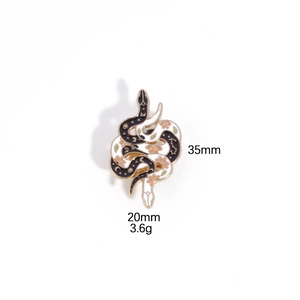 Artistic intertwined black and white snakes brooch with gold moon and stars patterns
