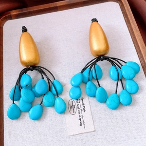 Close-up of bohemian tassel earrings with matte gold wood and turquoise blue beads