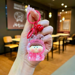 Close-up of cute cartoon doll keychain with pink glitter shell and red bell detail