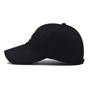 Detail of a black cotton baseball cap showing side red woven label and 3D embroidery