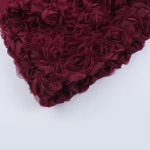 Gros plan d'appliques florales de roses 3D bordeaux sur tissu de robe de soirée en mousseline