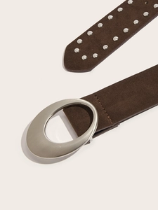 Detail de la ceinture en daim marron avec rivets argentes et boucle ovale brossée