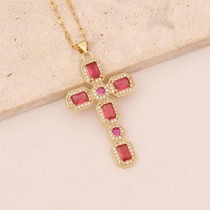 Detailed macro view of 18K gold-plated cross pendant with red and pink crystals