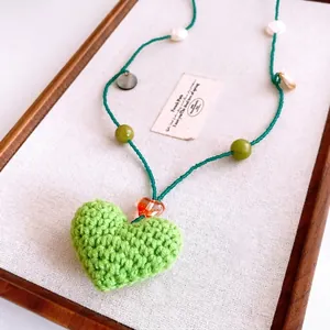 Vue détaillée du collier fait main avec cœur crocheté vert et perles élégantes