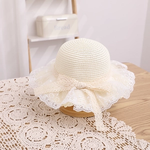 Detail of children's straw hat with delicate white lace trim and large woven bow tie