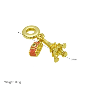 Macro detail of a gold camera and Eiffel Tower charm with red enamel details and dimensions