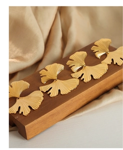 Detailed view of golden ginkgo leaf earrings with fine radial texture and metallic finish
