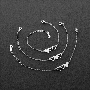 Detailed view of set of three silver heart pendants with lobster clasp on dark background