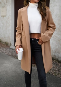 Street style view of a camel wool coat paired with a white turtleneck and black jeans
