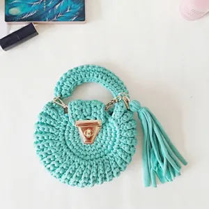 Detail of tiffany blue crochet round bag with metal clasp, fringe and fashion accessories