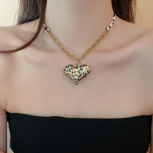 Detail of a leopard print heart pendant with golden metal chain and fabric ribbon strap