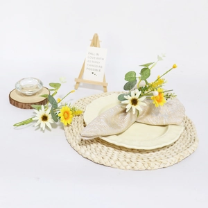 Close-up of artificial daisy napkin ring with green leaves and yellow berries on table