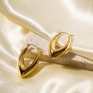 Detail of gold U-shaped hollow earrings on silk background with soft shadows