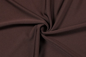 Detailed close-up of dark brown knitted fabric texture with elegant drape and fine weave