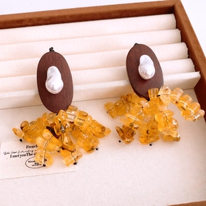 Detail view of vintage oval resin earrings with wood base, pearl and amber bead tassels