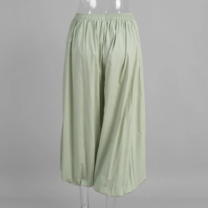 Detail of light green cotton harem pants showing elastic waist and tapered leg design