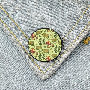 Cartoon frog and mushroom round badge pinned on a denim pocket with yellow stitching