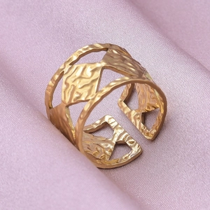 Detailed view of golden hollow geometric ring with vintage textured finish on silk fabric