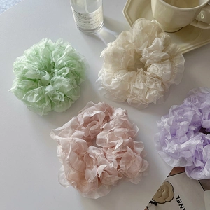 Detail of four colorful lace organza scrunchies in pastel green cream pink and purple