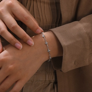 Detail of silver cross-shaped link bracelet on wrist with elegant metallic finish