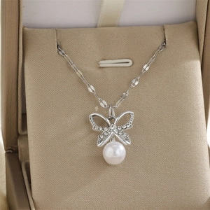 Détail du collier pendentif papillon argenté avec cristaux et perle dans un écrin cadeau