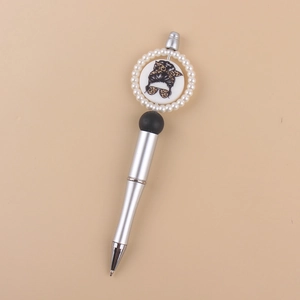 Macro shot of silver ballpoint pen featuring a messy bun silhouette with pearl accents