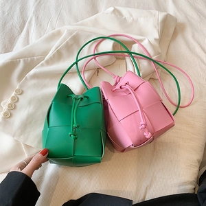 Mini woven drawstring bucket bags in green and pink with crossbody straps