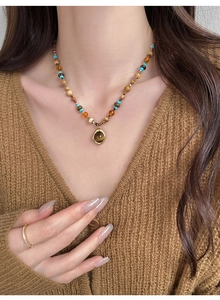 Détail de collier de perles bohème avec pendentif ambré doré porté par un mannequin