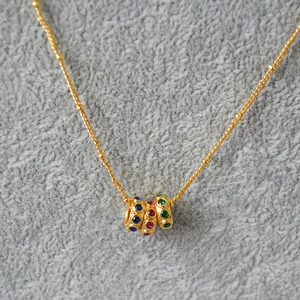 Détail du collier plaqué or avec perles festonnées et pierres de zircon colorées