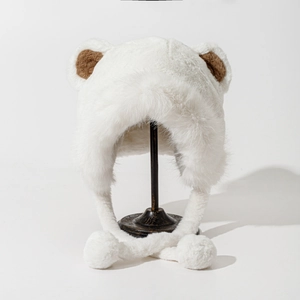 Detail of white faux fur winter hat with cute brown bear ears and soft plush pom-poms