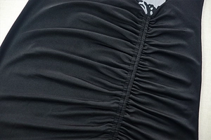 Detailed close-up of ruched center seam and textured black fabric on slim fit dress
