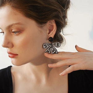 Primo piano di eleganti orecchini a fiocco nero con cristalli indossati da una modella