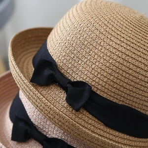 Close-up of woven straw sun hat texture with elegant black ribbon bow detail