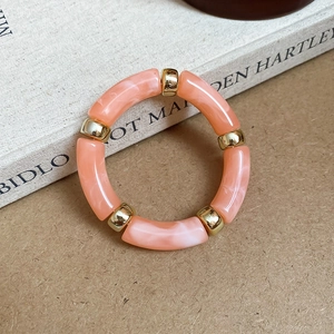 Close-up of pink marble acrylic bangle with golden metal spacer beads on book