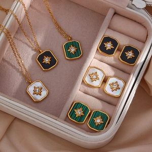 Detail of vintage gold star necklaces and square shell earrings in a jewelry box