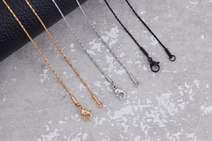 Detailed view of gold, silver and black metal chain necklaces with lobster clasps