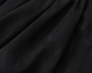 Gros plan sur la texture du daim noir avec des plis naturels sur une robe courte
