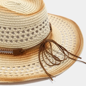 Close-up of hollowed-out straw hat with sunflower studs and long tassel suede band
