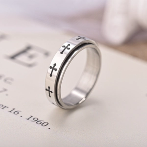 Detail of a rotating stainless steel cross ring with black gothic patterns on a book page