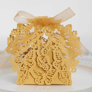 Close-up of golden hollow butterfly candy box with laser-cut details and organza ribbon