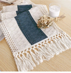 Detail of two-tone cream and navy linen table runner with knotted tassels on wood