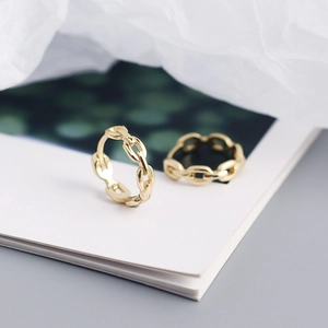 Close-up of gold chain link hoop earrings on a blurred book background with soft lighting