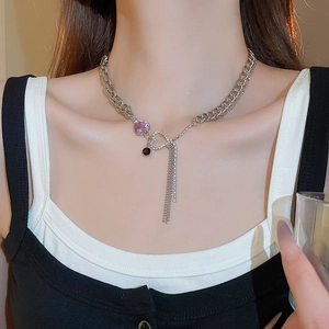 Close-up of silver chain necklace featuring a purple heart gem and rhinestone tassels