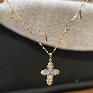 Macro shot of bicolour cross pendant with marquise zircons and brushed gold finish