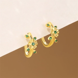 Detail of floral gold earrings with green gemstones and elegant leaf patterns