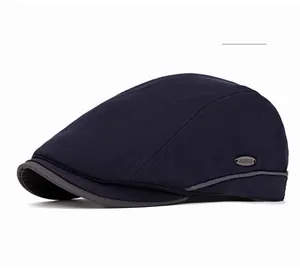 Detail of navy blue herringbone flat cap with metallic logo plaque and stitching