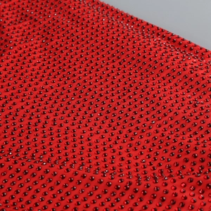 Macro detail of red rhinestone fabric with dense sparkling crystals for evening dress